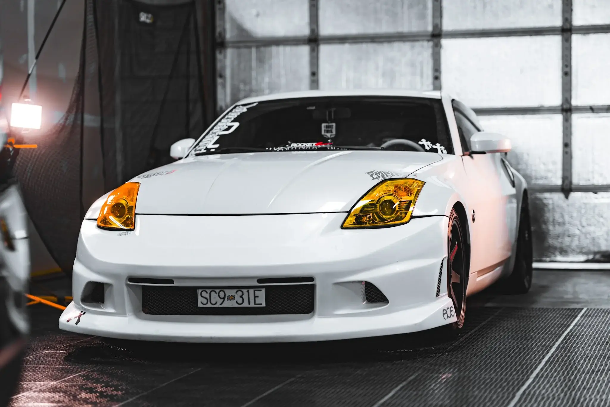 White Nissan 350Z with yellow-tinted headlights inside the shop