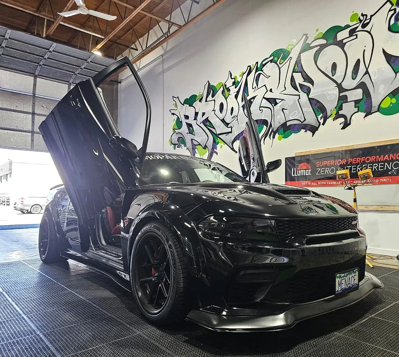 Black Dodge Charger with vertical doors inside the shop