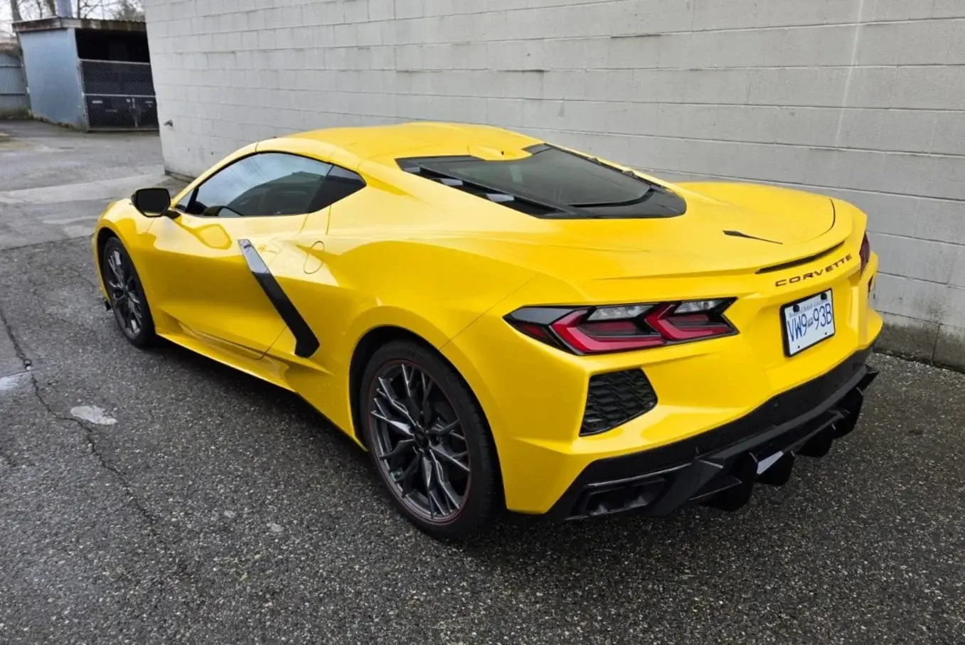 Rear three-quarter of a yellow Corvette C8 with tinted glass