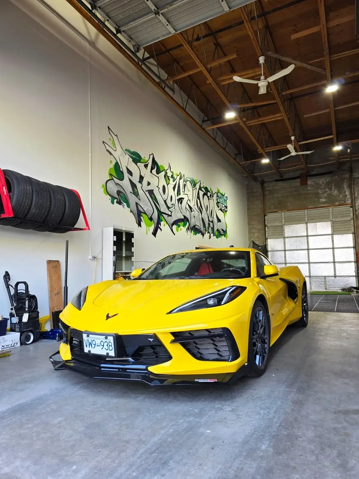 Yellow Chevrolet Corvette C8 inside the shop under the graffiti wall