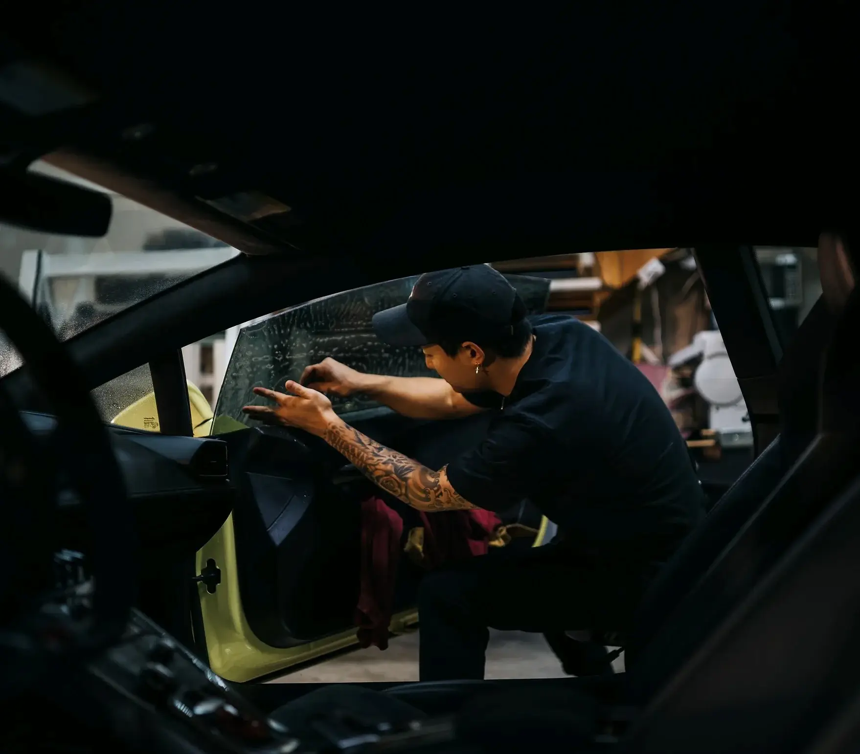 Technician fitting film to a rear door window from inside the car