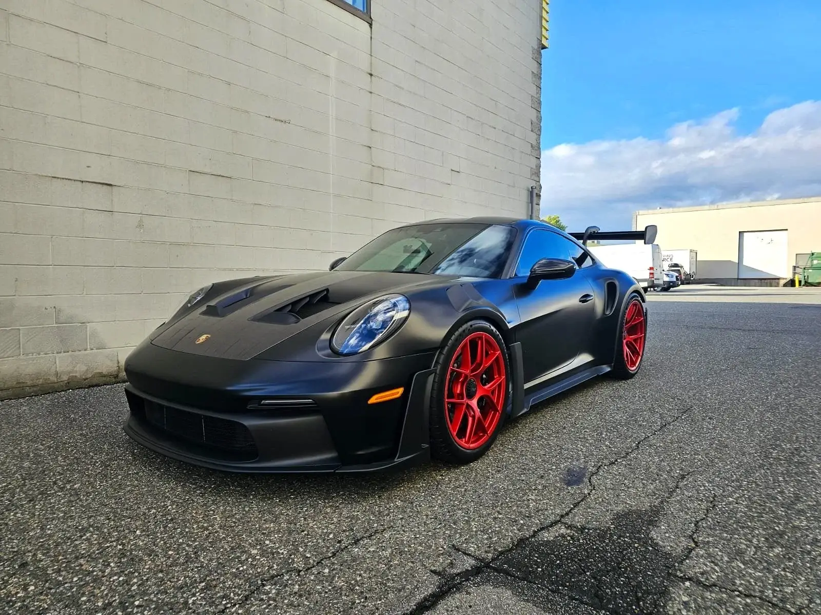 Front view of a satin black Porsche 911 GT3 RS outside the shop
