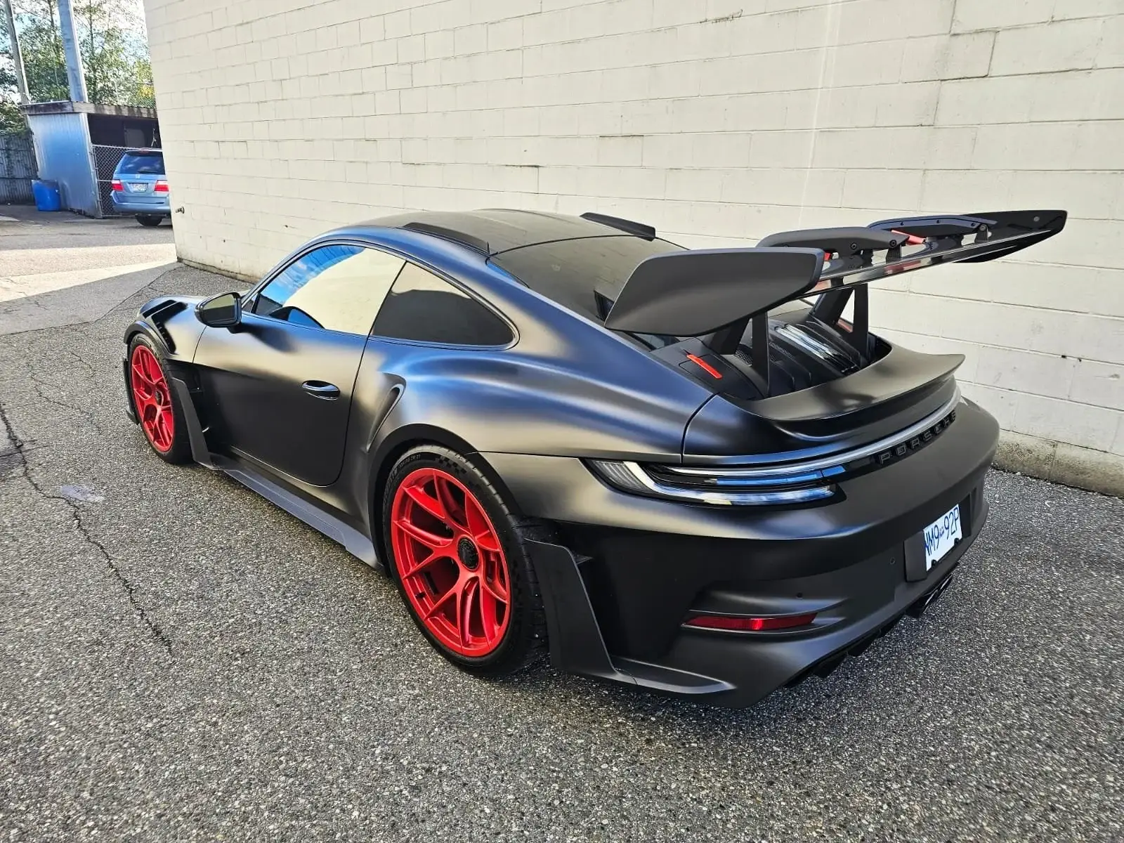 Rear three-quarter view of a satin black Porsche 911 GT3 RS with red wheels