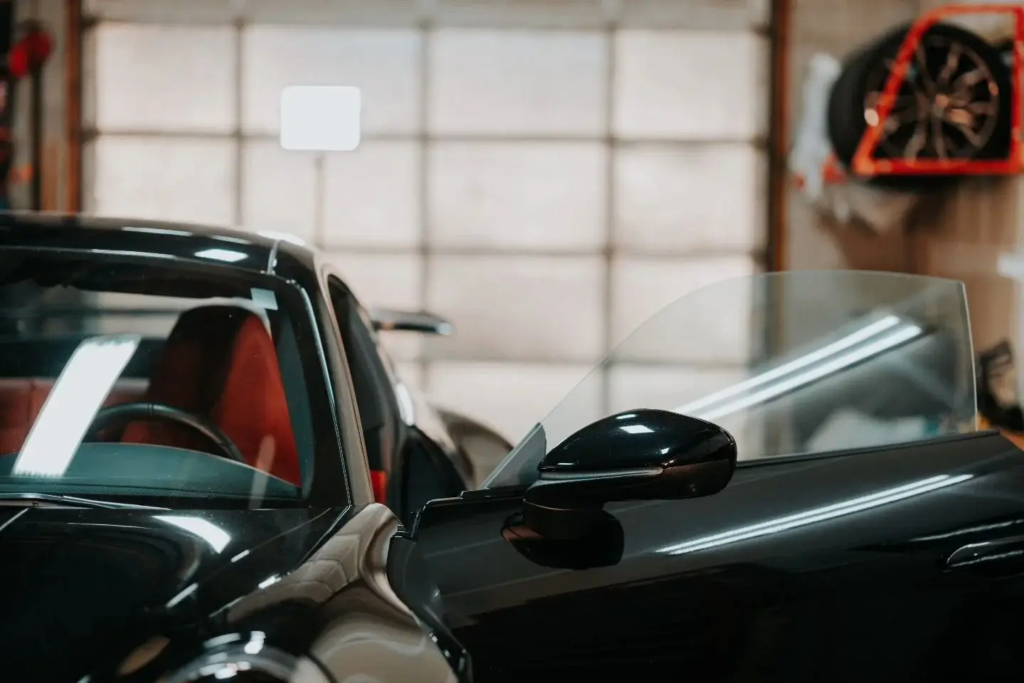Black Porsche 911 with red interior and tinted glass inside the shop