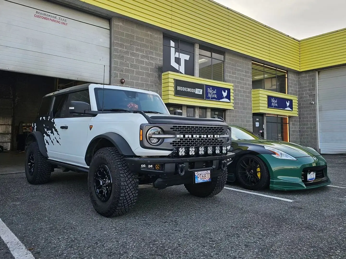White Ford Bronco with a custom vinyl wrap parked outside the shop