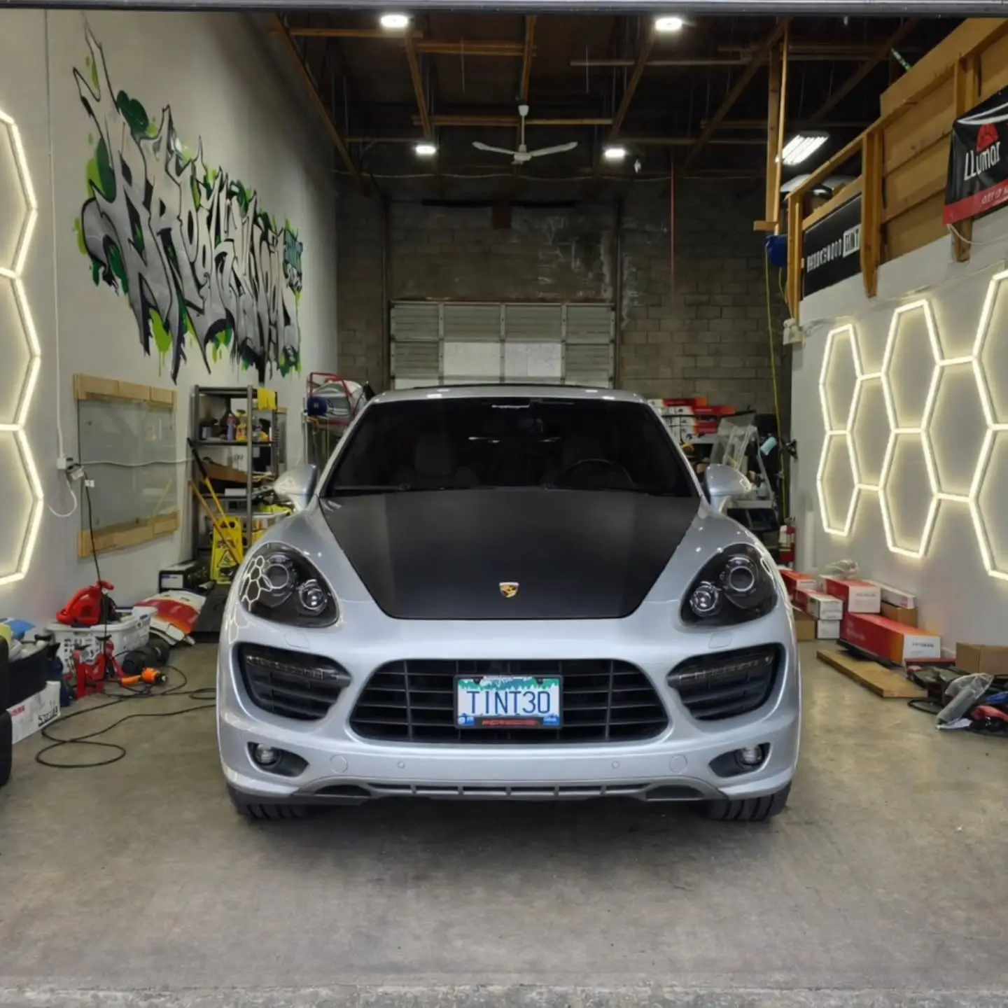 White Porsche Cayenne with a TINT30 plate inside the shop