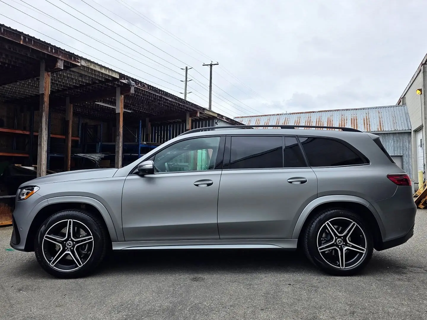 Side profile of a Mercedes GLS wrapped in Avery Matte Metallic Gunmetal vinyl, parked outside the shop in Langley under a grey sky