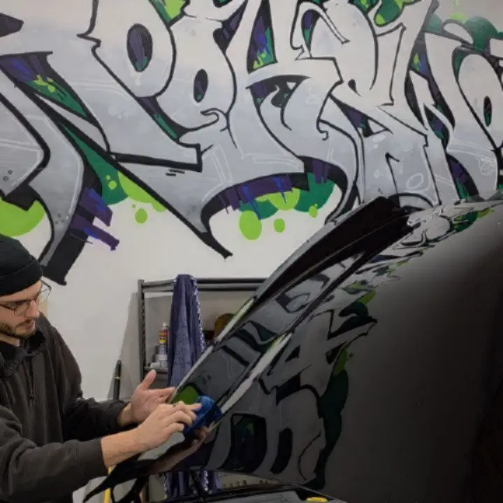 Johnny, the shop's owner, trimming film in front of the graffiti wall
