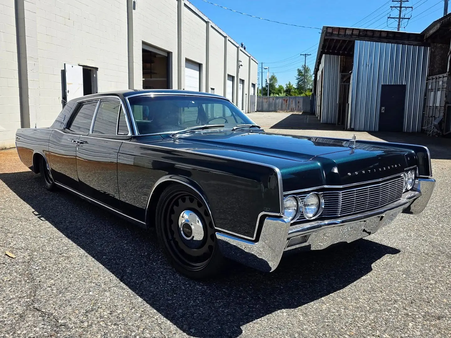 1967 Lincoln Continental in emerald green, lowered on air suspension, outside the shop
