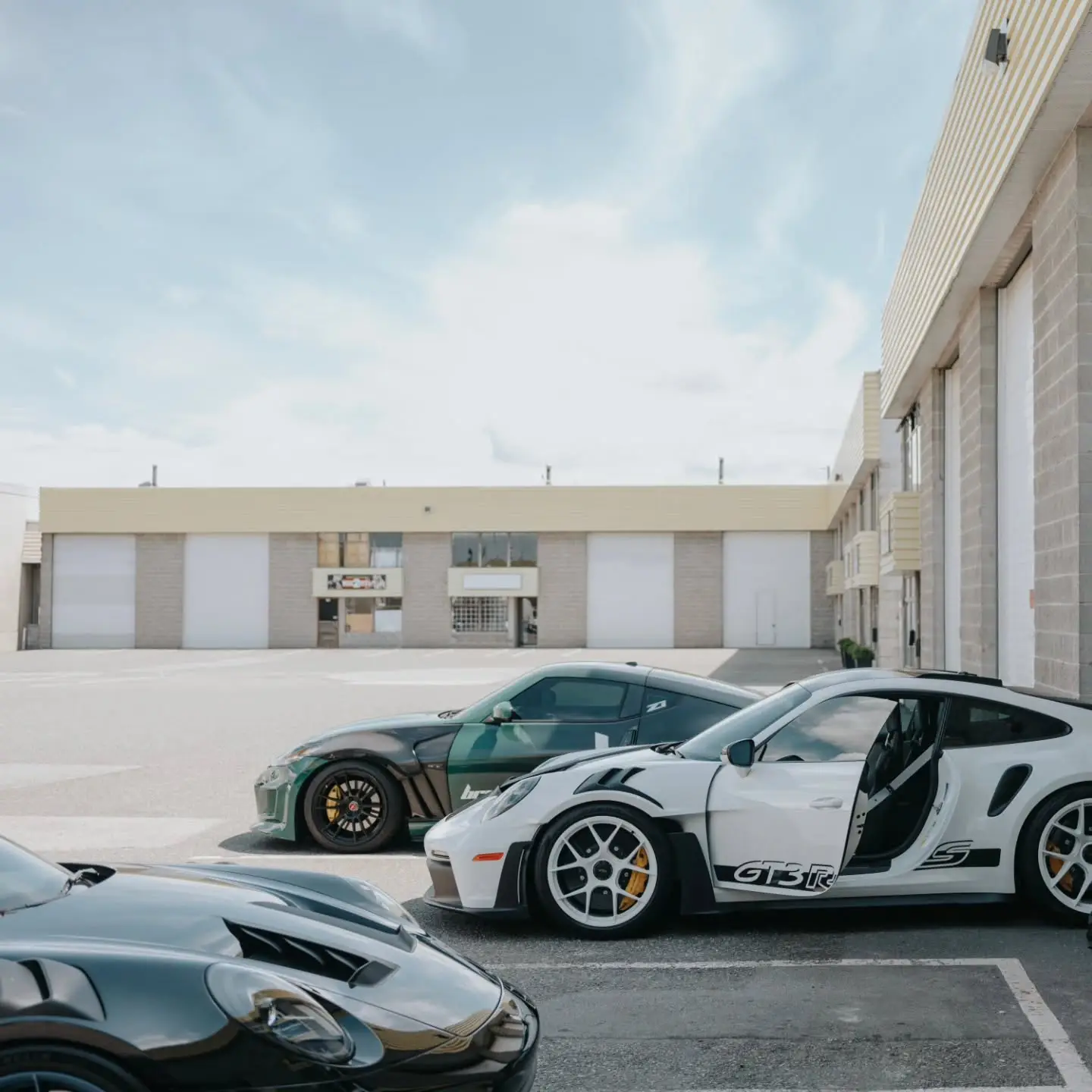 Two Porsche 911s, a GT3 RS and a Turbo S, parked outside the shop