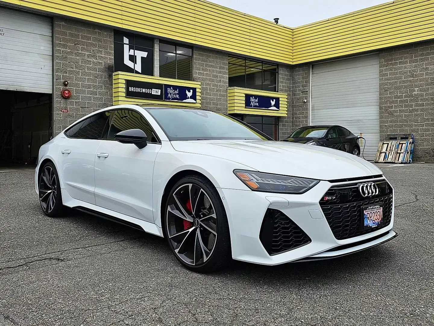 White Audi RS7 with tinted windows parked outside the shop