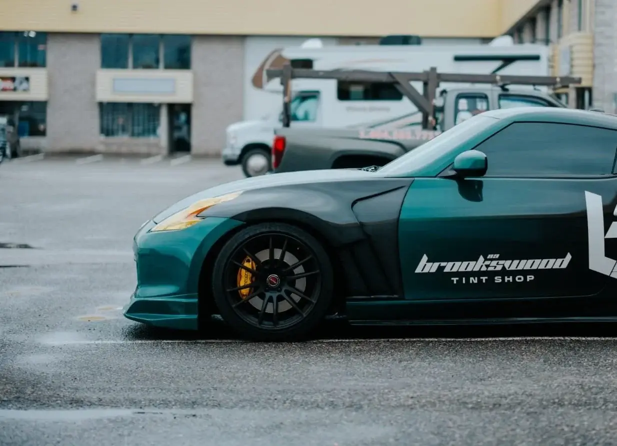 Green Nissan 370Z with Brookswood Tint Shop livery in the parking lot
