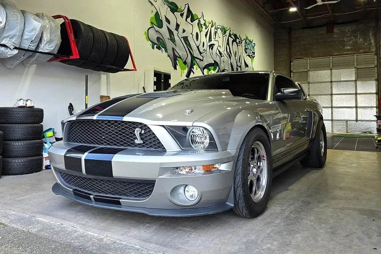 Silver Shelby GT500 with black stripes inside the shop
