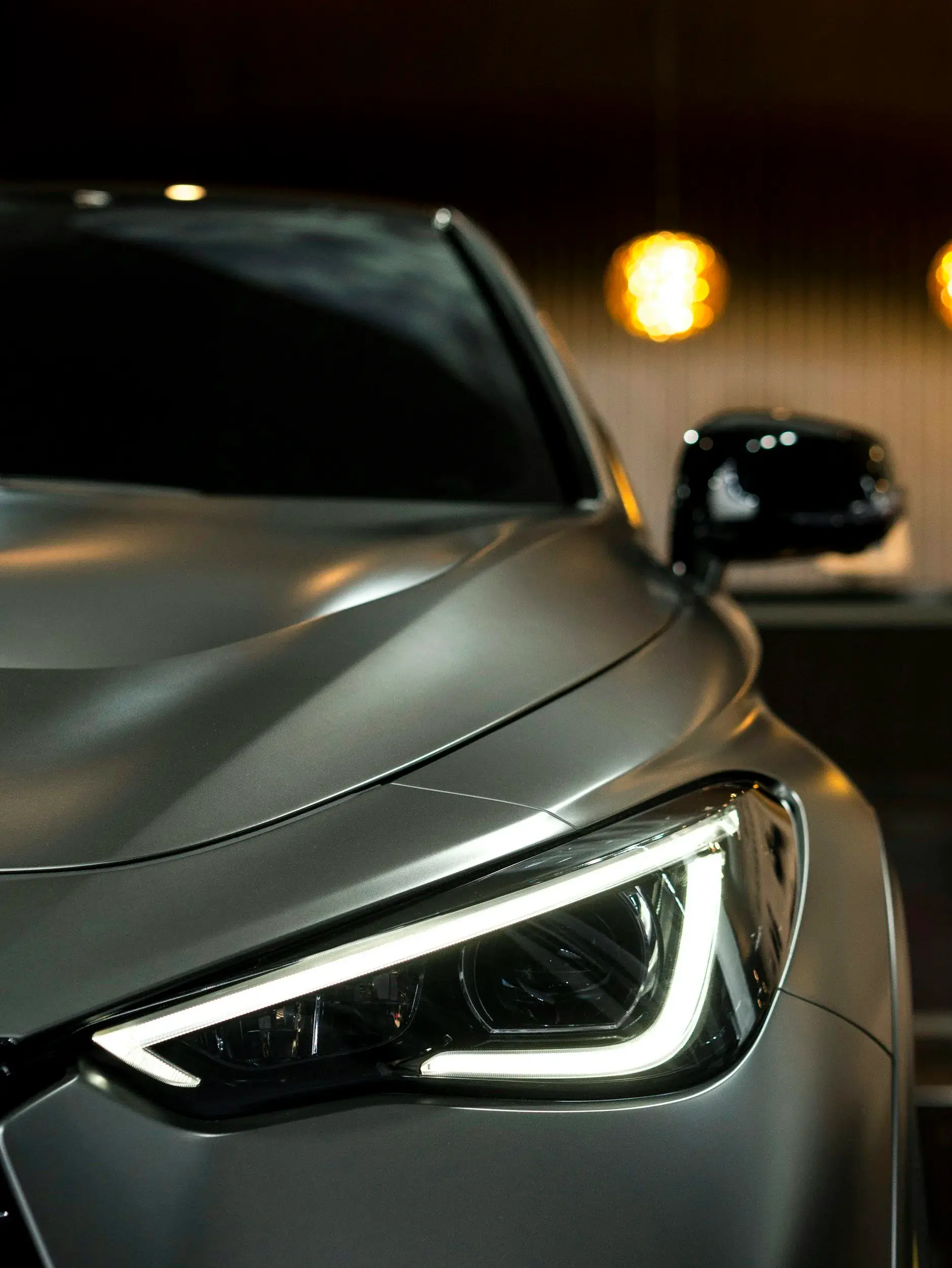 Close-up of a crisp, clear LED headlight with its light strip switched on, set into the front of a grey car